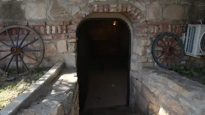 a brick tunnel with two wagon wheels on a wall at Къща за гости АЛЛА in Byala