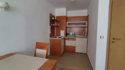 a small kitchen with wooden cabinets and a table at Апартамент Полюси 2 in Sunny Beach