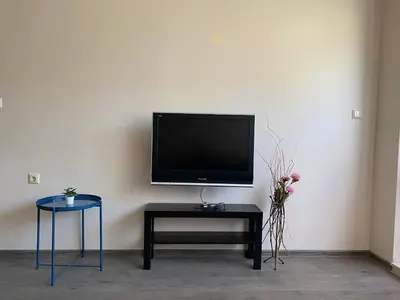 a flat screen tv sitting on a wall with a table and stool at Apartment Starfish in Varna City