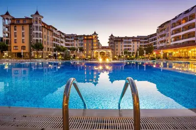 a large swimming pool with chairs in front of buildings at One bedroom guest suite in Sunny Beach