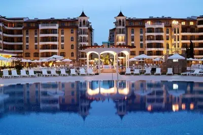 a large pool with chairs and buildings in the background at One bedroom guest suite in Sunny Beach