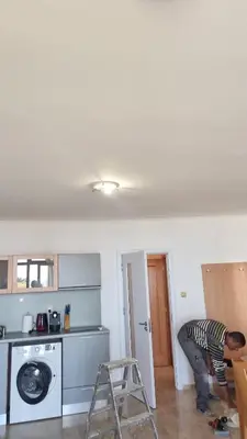 a man working in a kitchen with a washing machine at Luxsus Apartment Diamond Sveti Vlas in Sveti Vlas