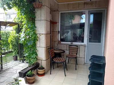 a patio with two chairs and a table next to a window at къща за гости Градина in Aheloy