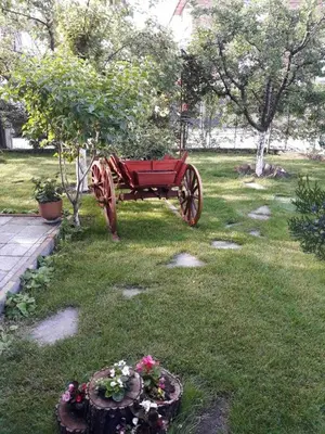 a red wagon sitting in the grass in a yard at къща за гости Градина in Aheloy