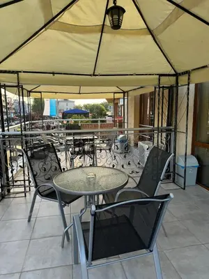 a table and chairs under an umbrella on a patio at Къща за гости Деневи in Primorsko