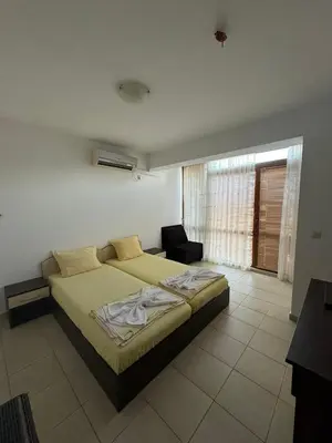 a bedroom with a bed and a chair in it at Къща за гости Деневи in Primorsko