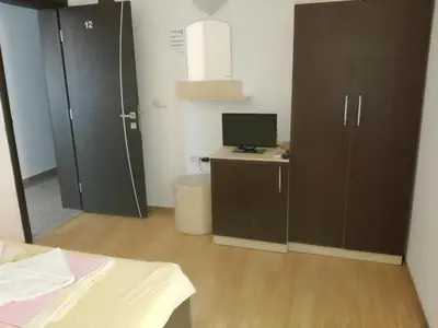 a room with a bed and a desk with a computer at Къща за гости Деневи in Primorsko