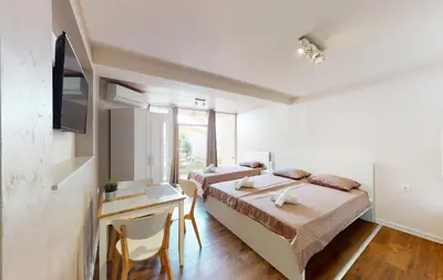 a bedroom with two beds and a desk and a tv at Markoni 5 in Burgas City