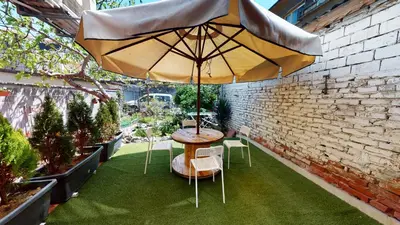 a table and chairs with an umbrella in a garden at Markoni 5 in Burgas City