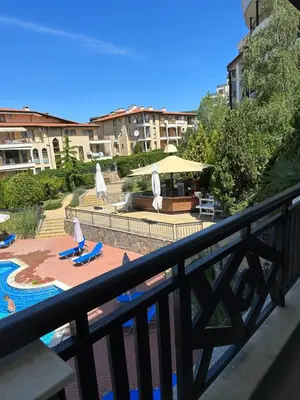 a balcony with a view of a pool with chairs and umbrellas at Александър Студио in Sveti Vlas