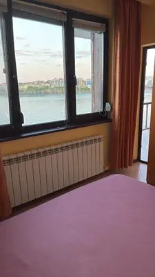 a bedroom with a large window with a view of the water at Къща за гости Кая in Sozopol