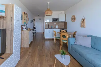a living room with a blue couch and a kitchen at Smokini Beach Apartment in Sozopol