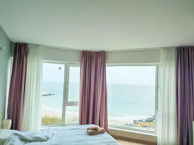 a bedroom with a large window with a view of the ocean at Apartment Sunrise Pomorie in Pomorie
