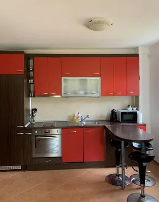 a kitchen with red cabinets and a wooden table at Апартамент Silver Star in Sozopol