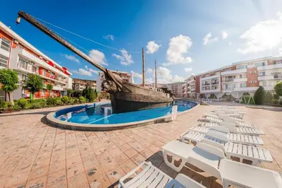 a group of white lounge chairs and a boat in a courtyard at Apartmán TTT in Burgas City