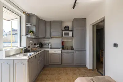 a kitchen with gray cabinets and a sink and a window at Promenade Rooftop Flat in Varna City