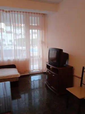 a living room with a tv on a wooden dresser at Апартамент Браво in Sunny Beach
