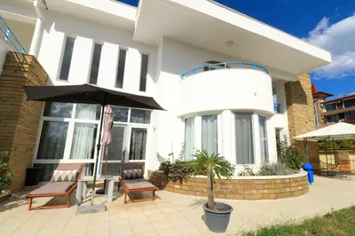 a house with two chairs and an umbrella on a patio at Ravda Residence in Ravda