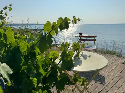 a table and a chair next to the ocean at Cozy 1 bed apartment in Lesso Complex (Ravda, Nessebar) in Ravda