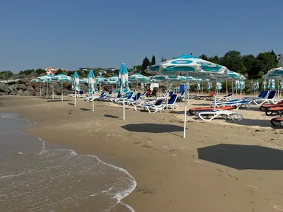 a group of chairs and umbrellas on a beach at Cozy 1 bed apartment in Lesso Complex (Ravda, Nessebar) in Ravda