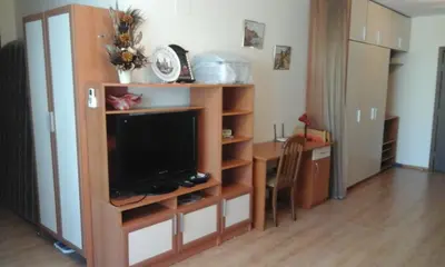 a living room with a tv and a table with a desk at Cozy 1 bed apartment in Lesso Complex (Ravda, Nessebar) in Ravda