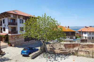 a blue car parked next to a tree in a town at ВИЛА ТЪРТЕФФ in Nesebar