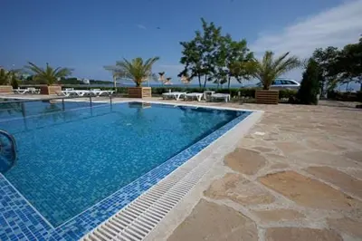 a large swimming pool in a resort with tables and chairs at Vilmar Studio in Pomorie