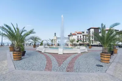 a fountain in a plaza with palm trees and buildings at Oasis Resort & Spa Cozy Studio in Lozenets