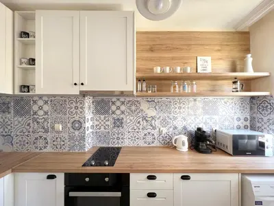 a kitchen with white cabinets and blue and white tiles at Lovely Apartment with Balcony in Pomorie Old Town by Flat Mаnаger in Pomorie