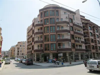 a tall building with cars parked in a parking lot at Rayski zalez in Pomorie