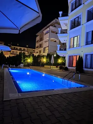 a swimming pool in front of a building at night at Horizon Apartament Gut in Sveti Vlas