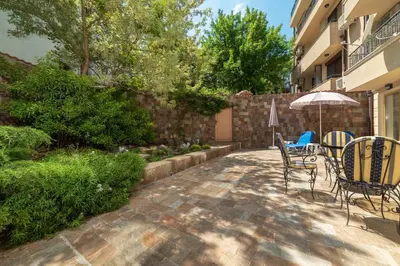 a patio with a table and chairs and an umbrella at Deluxe and Central Garden Apartment in Varna City