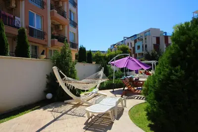 a patio with chairs and a hammock and an umbrella at Апартамент в Рейнбоу 3 in Sunny Beach
