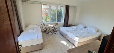 a room with two beds and a table and a window at Къща за гости Беглик Таш 2 in Primorsko