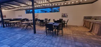 a dining room with tables and chairs and lights at Къща за гости Беглик Таш 2 in Primorsko