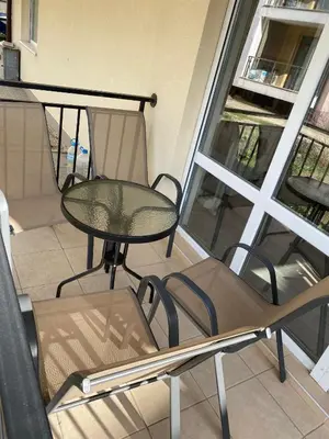 a balcony with a table and a chair and a window at Апартамент Ели in Obzor
