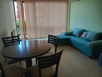 a living room with a blue couch and a table at Апартаменти СЪНИ БЕЙ in Sunny Beach