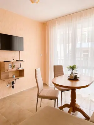 a dining room with a table and chairs and a tv at Blue Sky Apartments in Nesebar