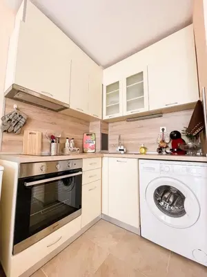 a kitchen with white cabinets and a washer and dryer at Blue Sky Apartments in Nesebar