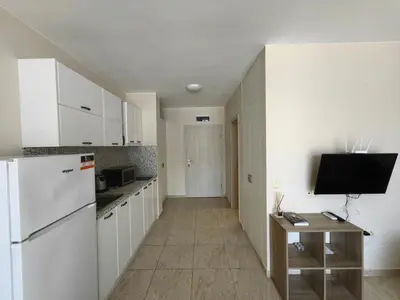 a kitchen with white cabinets and a white refrigerator at Studio in Sveti Vlas