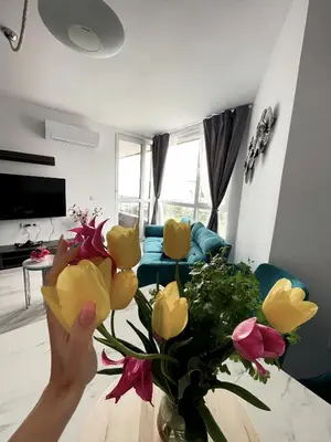 a person holding up a vase of flowers in a living room at Brand new first line Sea view 1 bedroom apartment in Burgas City