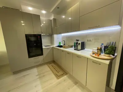 a kitchen with white cabinets and a wooden floor at Brand new first line Sea view 1 bedroom apartment in Burgas City