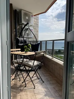 a table and chair on a balcony with a view of the ocean at Brand new first line Sea view 1 bedroom apartment in Burgas City