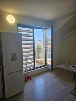 a kitchen with a refrigerator and a large window at Апартамент ИВАНОВИ Сарафово in Burgas City