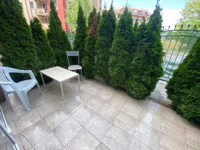 a patio with a white table and chairs and trees at Stella Polaris 1 Apartments in Sunny Beach