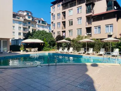 a swimming pool with chairs and umbrellas next to a building at Stella Polaris 1 Apartments in Sunny Beach