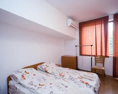 a bedroom with a bed and a chair and a window at ALEKS Top Center in Burgas City