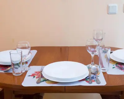 a wooden table with plates and wine glasses on it at ALEKS Top Center in Burgas City