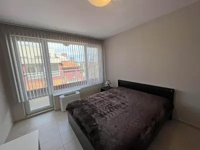 a bedroom with a bed and a large window at Valemar Apartments in Pomorie