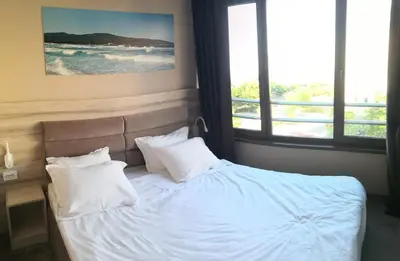 a bed with white sheets and pillows in a bedroom at euroHOTEL Primorsko in Primorsko